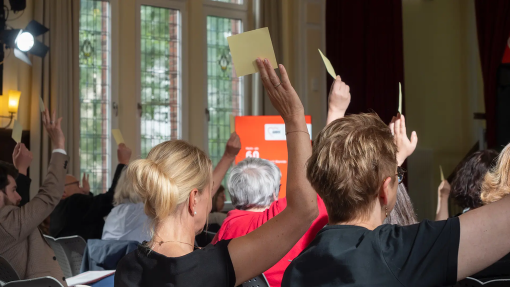Das Foto zeigt Menschen von hinten bei der Wahl per Akklamation
