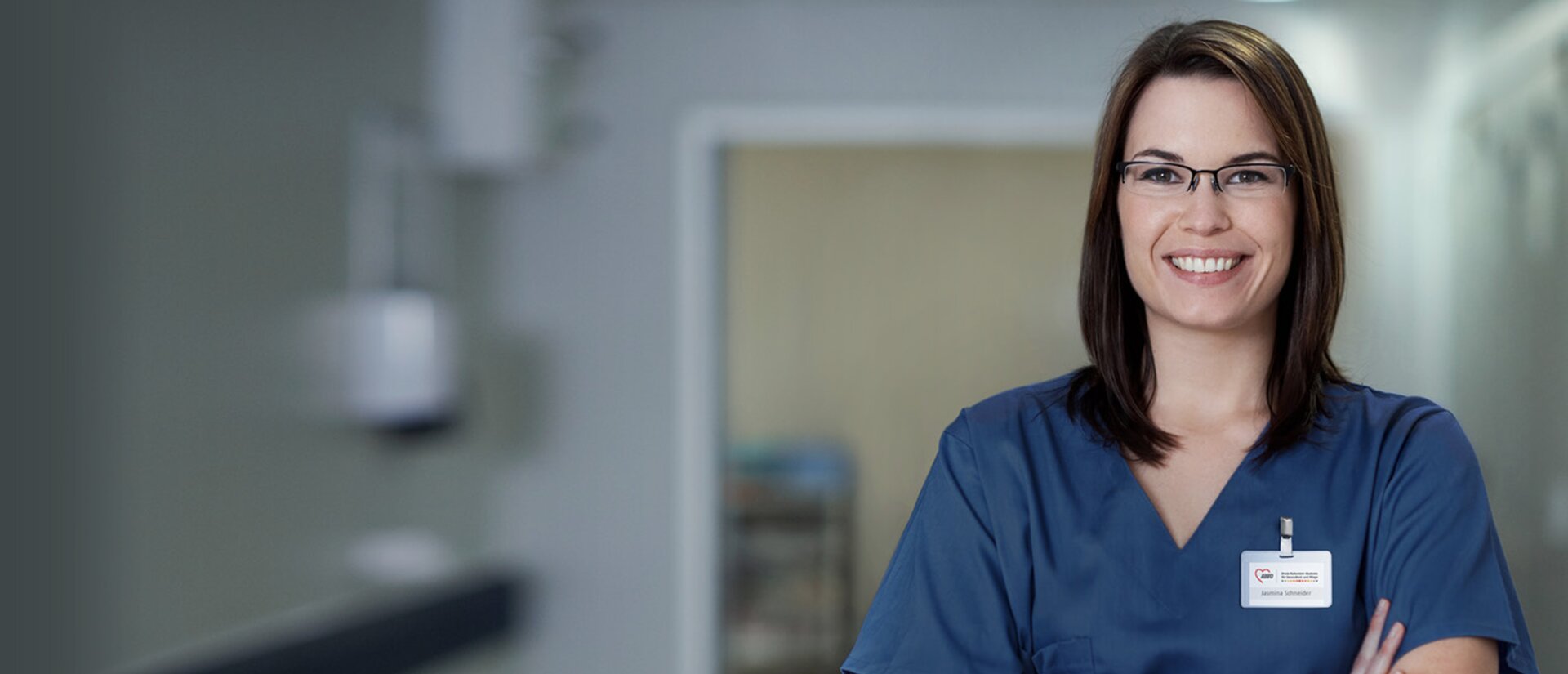 Das Foto zeigt eine junge Frau in typischer Pflegeberufs-Kleidung